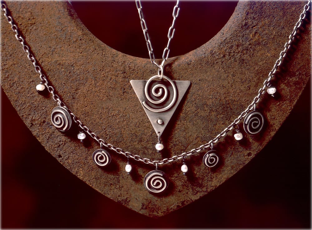 Spiral design silver necklaces displayed on rusty background Product Photography
