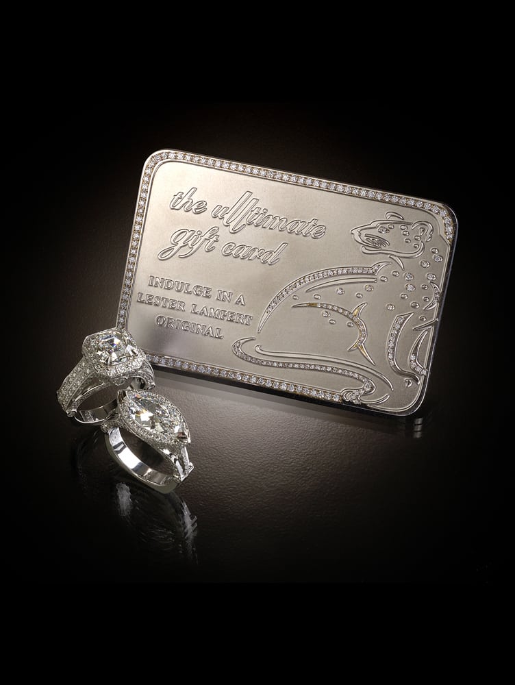 Product shot featuring dramatically lit platinum and diamond gift card with the inscription "the ultimate gift card" and a leopard shape all with two diamond rings in foreground on black background Product Photography