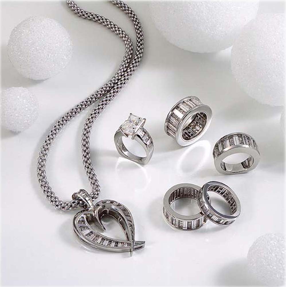 Platinum 5 diamond ring collection with platinum and diamond heart pendant on woven platinum chain on white background and styrofoam ball props Product Photography