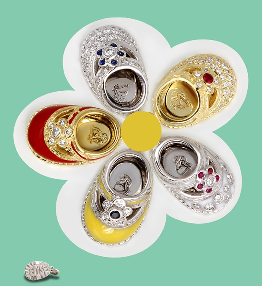Fancy gold and silver baby shoe charms with diamonds rubies and sapphires arranged in a flower pattern with a smaller charm showing the sole reading "ELiSE" Product Photography