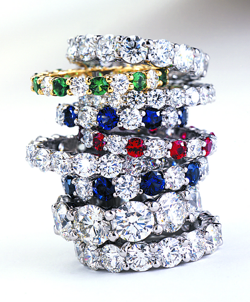Stack of nine diamond ring, all encircled with large diamonds, one with emeralds, one with rubies and two with sapphires. Product Photography