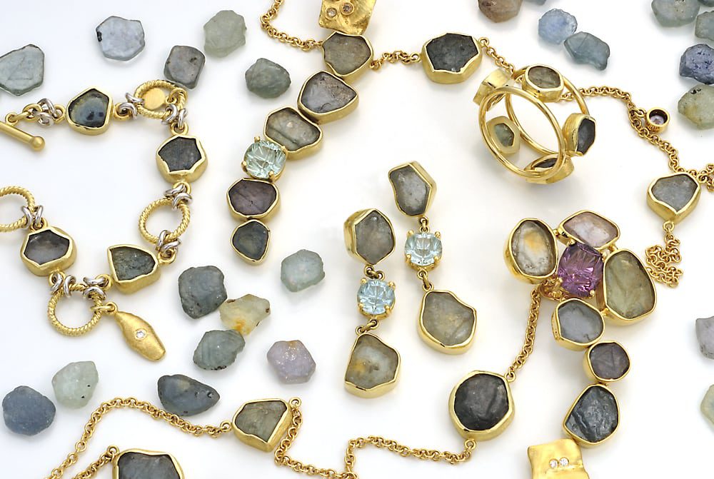 Raw sapphire grouping of loose stones, two necklace strands with pendants, bracelet, ring and earrings Product Photography