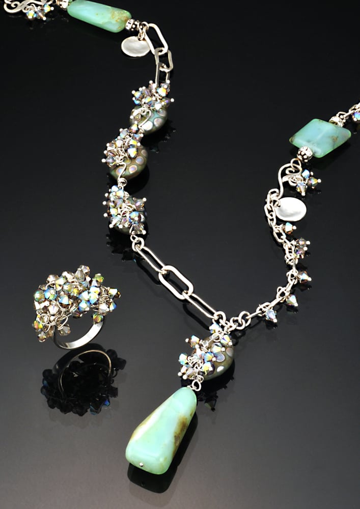 Necklace and ring set of silver links with rainbow stones and the necklace has blue polished stones