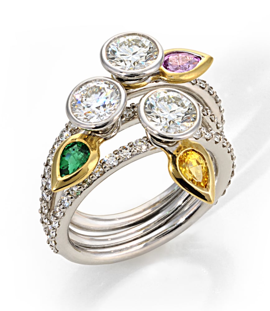 platinum ring stacking set of three rings, all with large round diamonds on top and spinning gold 'leaves' on each, one with an emerald, one with topaz and one with pink diamond. Product Photography