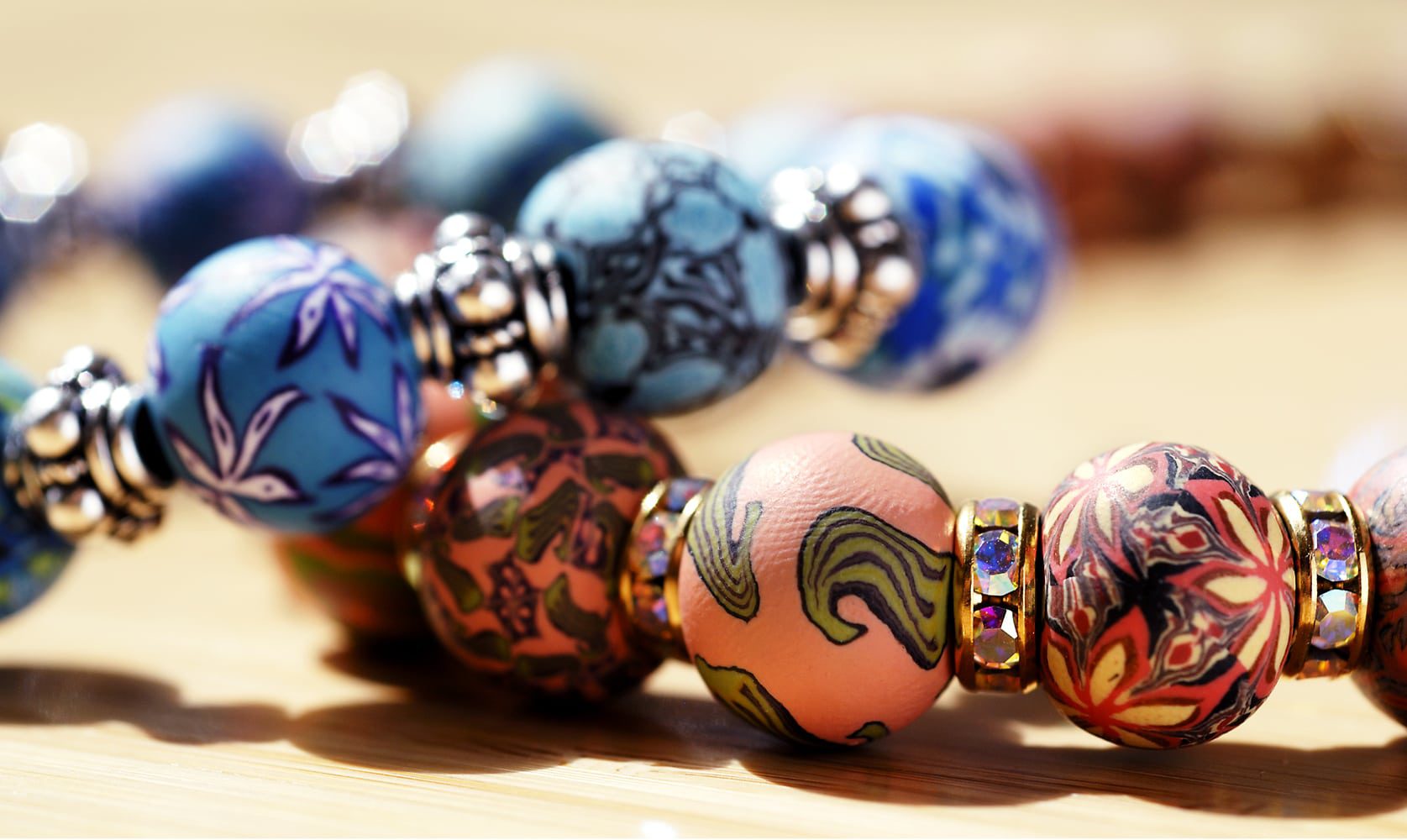 Hand made beads with intricate designs on two bracelets. One orange beads and one with blue beads piled on top